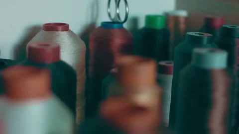 Spools of thread for sewing shoes in dark colors stand on a shelf Stock Footage 232615913