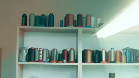 Spools of thread for sewing shoes in dark colors stand on a shelf Stock Footage 232615939