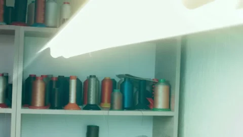 Spools of thread for sewing shoes in dark colors stand on a shelf Stock Footage 232615966