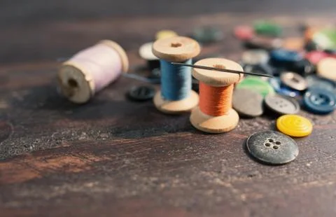 Spools of threads and buttons on old wooden table Stock Photos