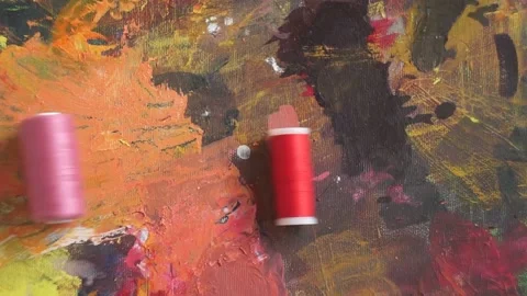 Spools of threads are rolling on painted background Stock Footage 222802229