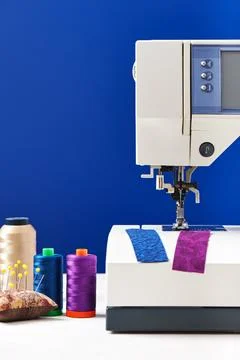 Spools of threads next to sewing machine on deep blue background Fotos Stock