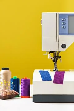 Spools of threads next to sewing machine on yellow background 库存照片