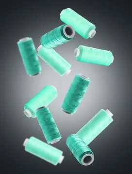 Spools of turquoise sewing threads falling on dark grey gradient background Stock Photos