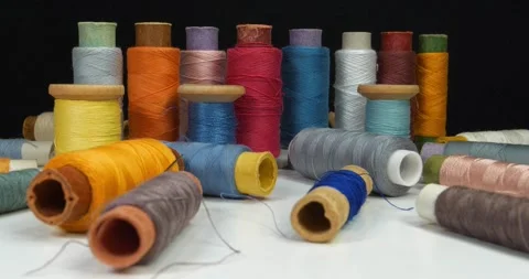 Spools with varicolored threads on black background. Cinema 4K zoom-out video Stock Footage 310557987