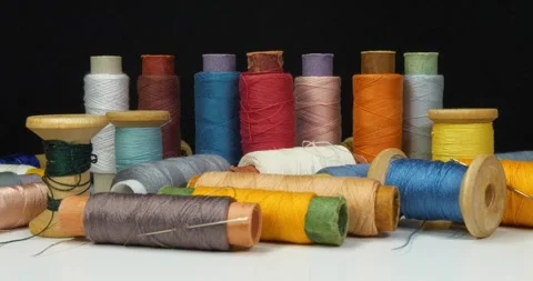 Spools with varicolored threads on black background. Cinema 4K zoom-out video Stock Footage 311125158