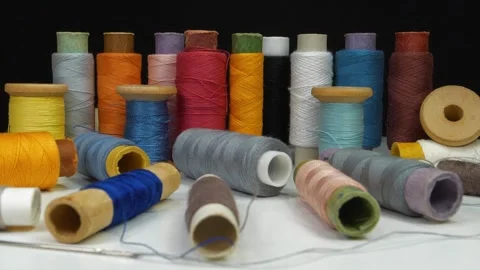 Spools with varicolored threads on black background, 4K zoom-in video Stock Footage 311453624