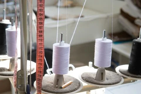 Spools of white and black thread stand on a sewing machine. Stock Photos