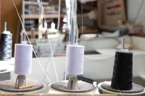 Spools of white and black thread stand on a sewing machine. Stock Photos