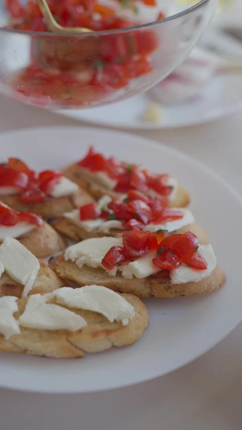 Spoon adds chopped tomato and herbs over mozzarella on toasted bread Stock Footage 339362536