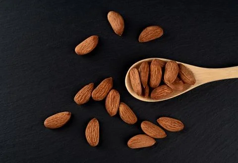 Spoon of almonds on a black background. Stock Photos