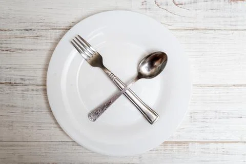 The spoon and fork are on an empty plate. Diet concept, intermittent fasting. Stock Photos