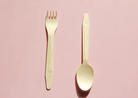 Spoon and fork on the pink background. Eco-friendly tableware from wood. Stock Photos