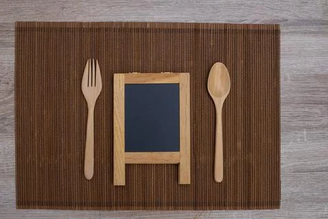 Spoon and fork on table with small black board. Stock Photos