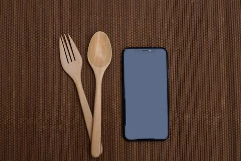 Spoon and fork on table with smart phone. Stock Photos