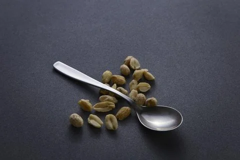 Spoon and peanuts on dark background food concept minimal photography Foto stock