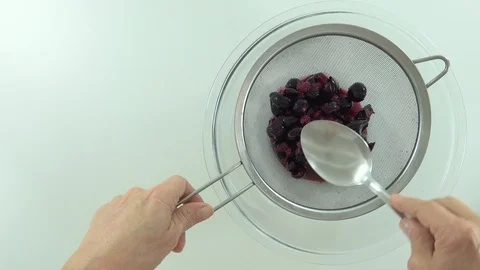 With spoon and sieve, preparing jam and sifting jaboticaba or jaboticaba. Stock Footage 128820731