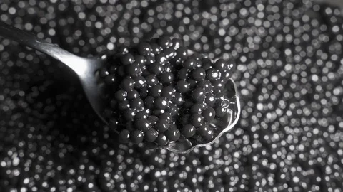 Spoon with black caviar on a background of rotating black caviar Video stock 123633359