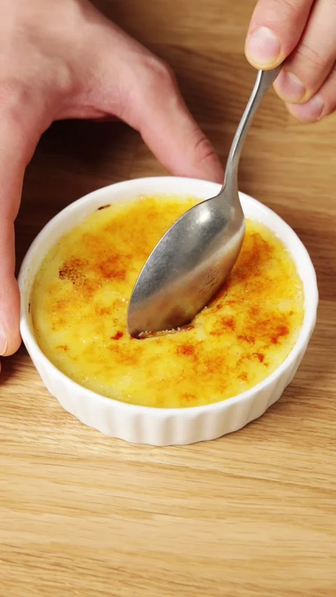 Spoon breaks crisp sugar crust and lifts crema catalana. Stock Footage 345273904