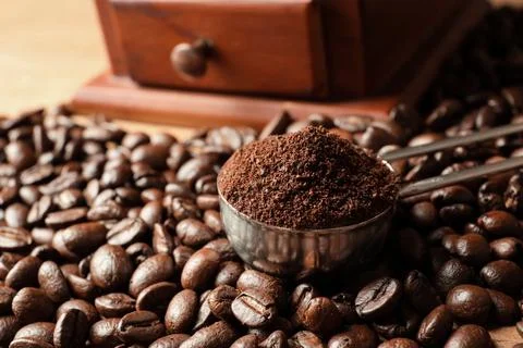 Spoon with coffee grounds and roasted beans on table, closeup Stock Photos