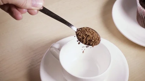 A spoon with coffee in his hand pours coffee into a cup slow motion Stock Footage 88867928