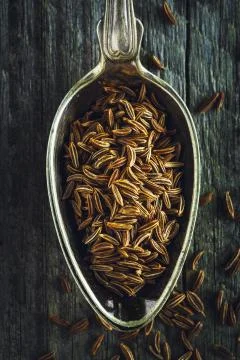 Spoon of cumin seeds on a wooden background Stock Photos