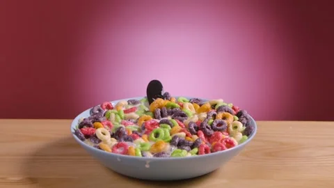 Spoon falls into deep bowl filled with multicolored corn rings and milk. Flakes Stock Footage 149134181