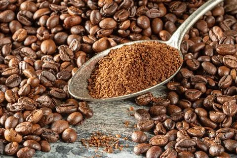 A spoon filled with ground coffee lies among a pile of coffee beans Stock Photos