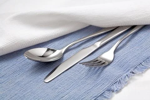 Spoon, fork and knife on blue tablecloth Stock Photos