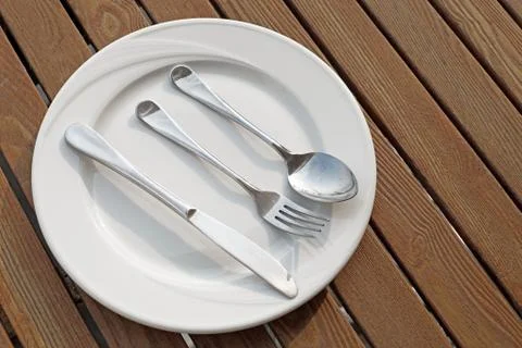 Spoon fork and knife on empty white plate Stock Photos