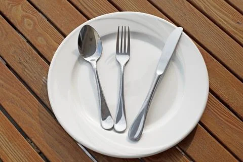 Spoon fork and knife on empty white plate Stock Photos