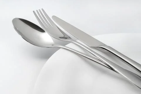 Spoon, fork and knife on white empty plate Foto stock