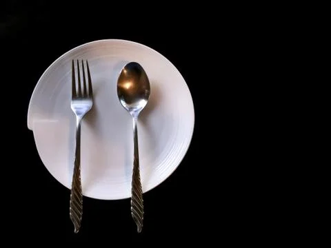 Spoon Fork and White Dish on Black Background Stock Photos