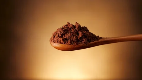 Spoon full of cocoa powder empty on golden background Video stock 105719108