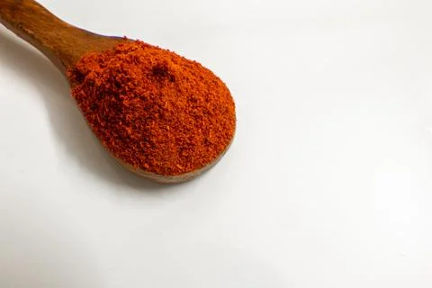 Spoon full of red chilli pepper powder over white background. Stock Photos