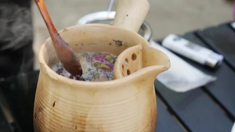 A spoon gently stirs milk tea in a clay teapot, mixing floral notes and creamy Stock Footage 309933317