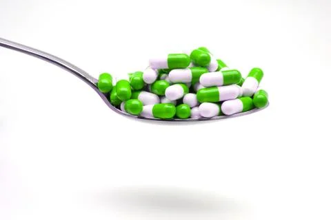 Spoon with green capsules Stock Photos