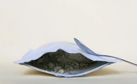 Spoon with green powder on the package. Stock Photos