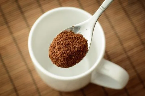 Spoon with ground coffee over the white empty cup Stock Photos