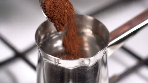Spoon ground coffee into turkish coffee pot. Slow motion. Stock Footage 145264957