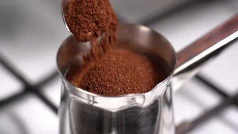 Spoon ground coffee into turkish coffee pot. Slow motion. Stock Footage 145264970