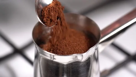 Spoon ground coffee into turkish coffee pot. Slow motion. Stock Footage 148976467