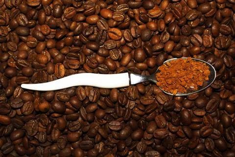 A spoon with instant coffee on a background of beans 写真素材