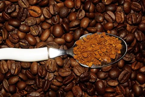 A spoon with instant coffee on a background of beans Stock Photos