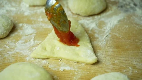 A spoon of jam putting into a triangular piece of dough Stock-Footage 221180989