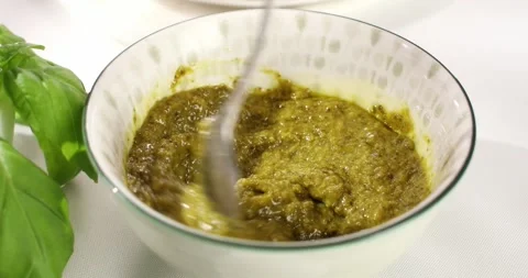 Spoon mix pesto in the bowl. angle view. sunny day. Stock Footage 243773689