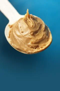 Spoon of nut oil on a blue background. Fotos de archivo