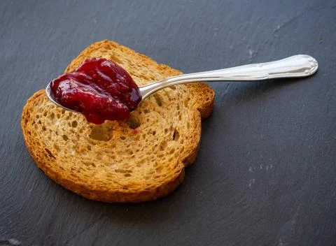  A spoon with raspberry jam on a slice of toast on a plate slate A spoon w... Stock Photos
