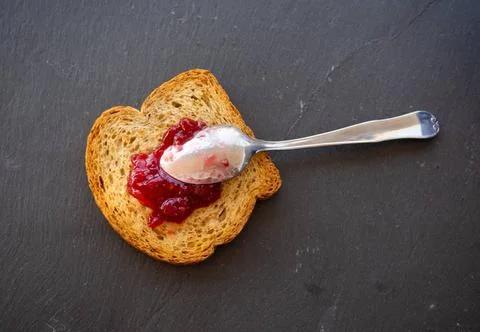  A spoon with raspberry jam on a slice of toast on a plate slate A spoon w... Stock Photos
