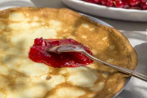 Spoon with red currant jam on a thin pancake. Traditional Russian food Stock Photos
